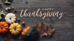 Happy Thanksgiving greeting script with colorful pumpkins, squash and leaves over dark wooden background
